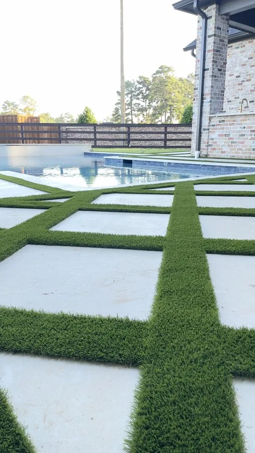 Artificial turf strips between large pavers beside a pool