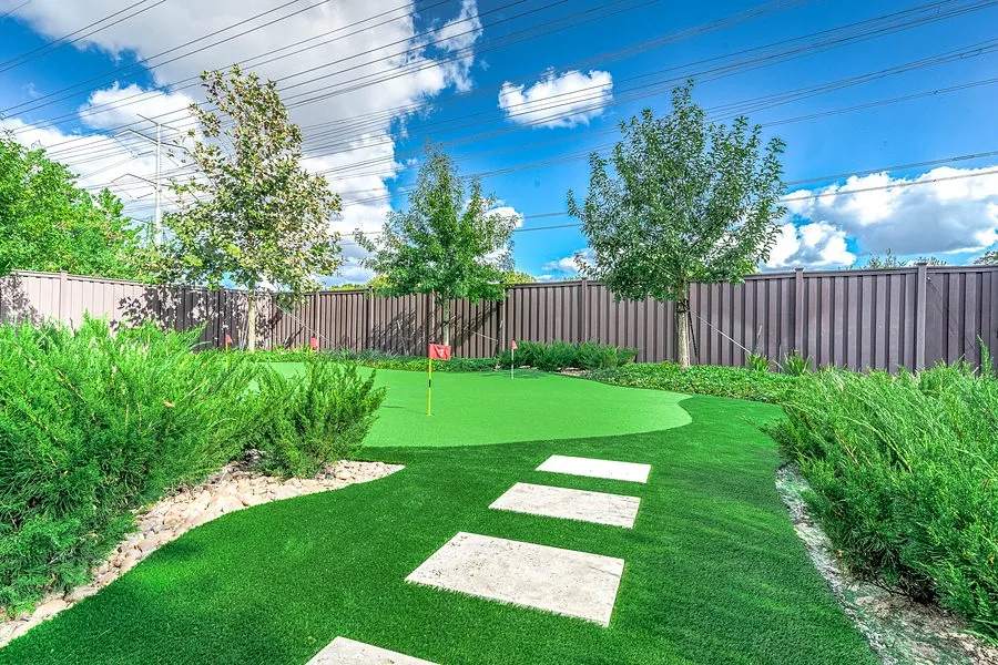Backyard putting green with a flagstick and stepping stones set in turf